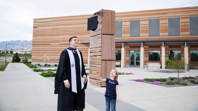 A man tosses his graduation cap with his daughter.